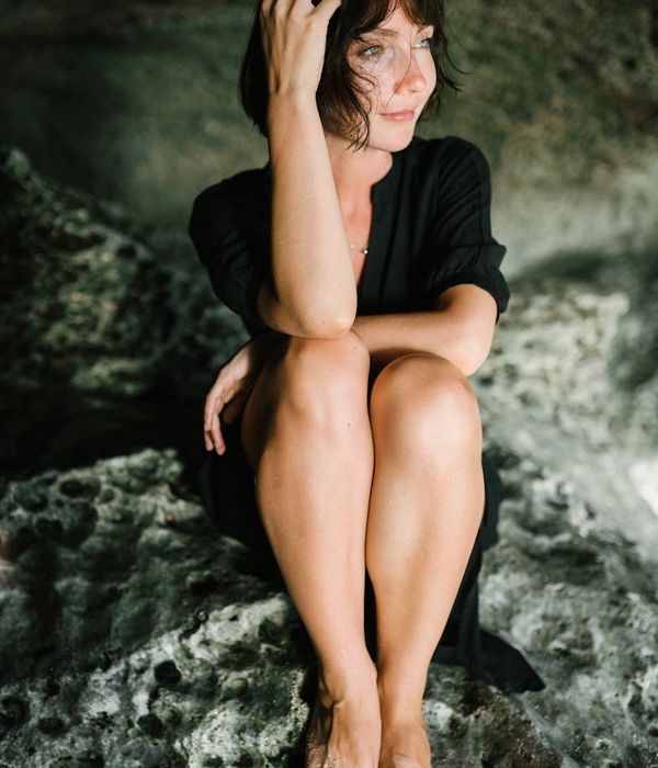 Person sitting in a meditative pose with a serene expression, surrounded by nature.